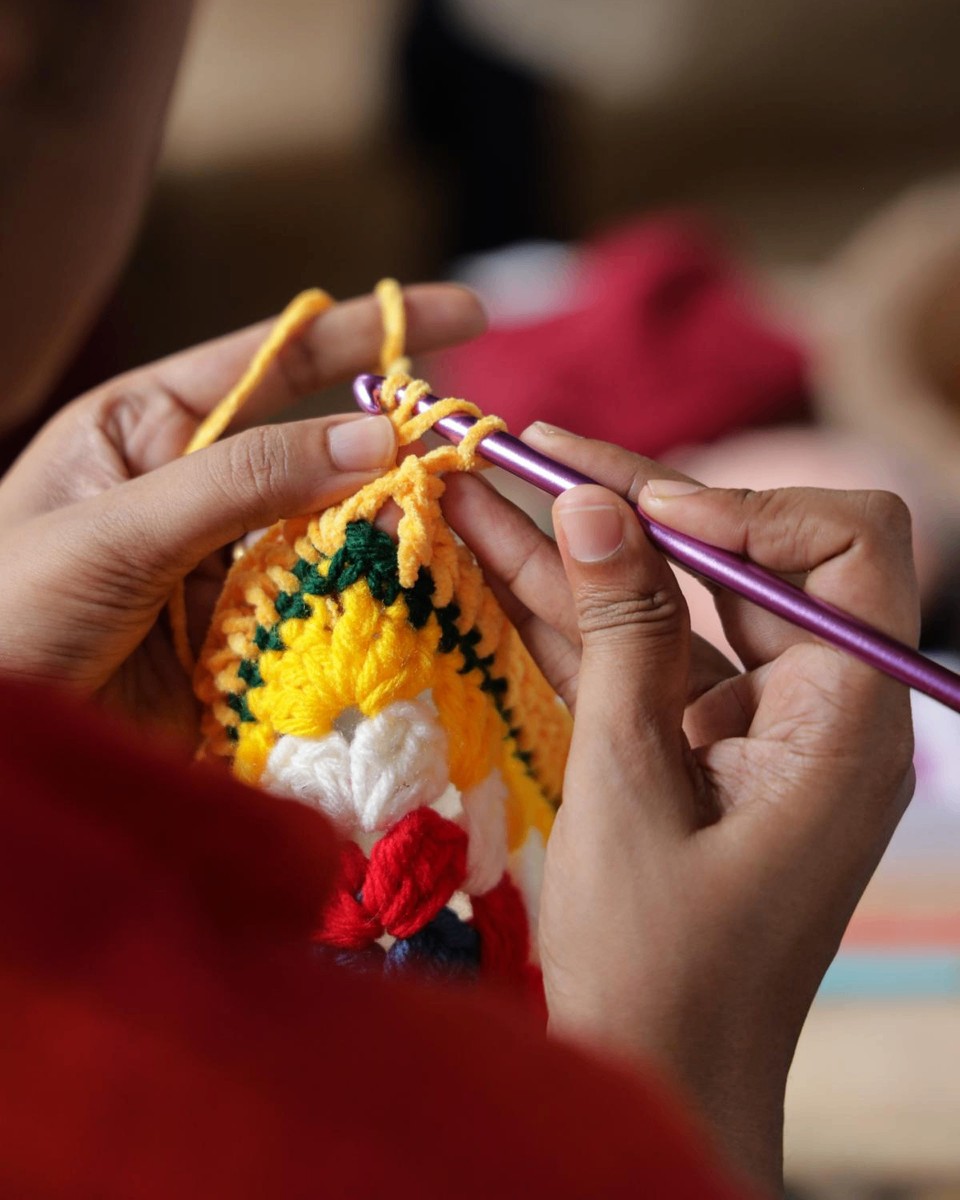 Close-up of an artisan's hands crocheting a colorful piece
